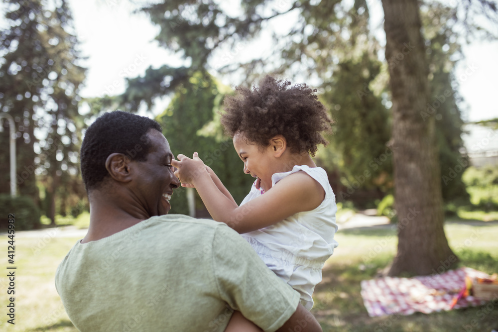 Sweet curly kid sitting playing with her dad and feeling happy Sweet curly kid sitting playing with her dad and feeling happy