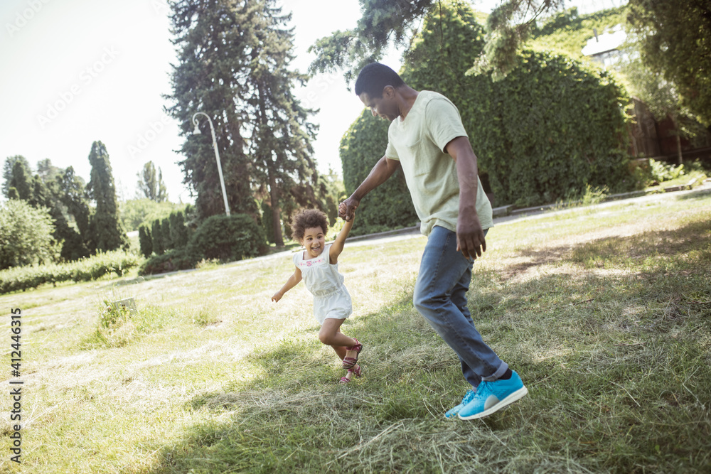 Fototapeta premium Cute curly kid sitting having great time with her dad