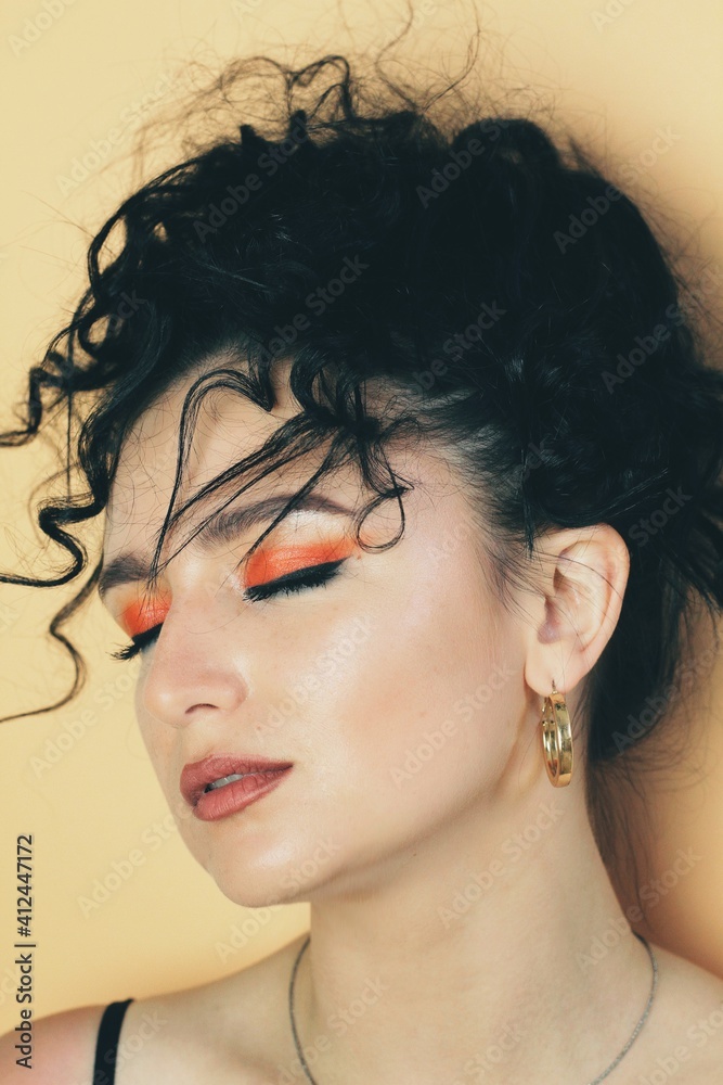 Beautiful young brunette model with bright make-up and curly hairstyle