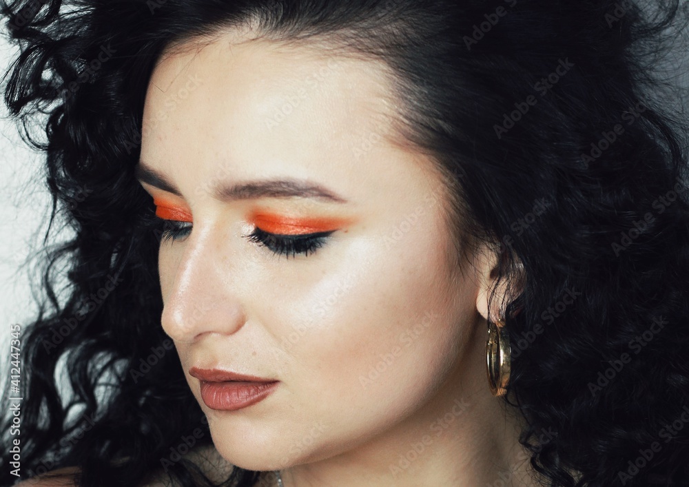 Beautiful young brunette model with bright make-up and curly hairstyle