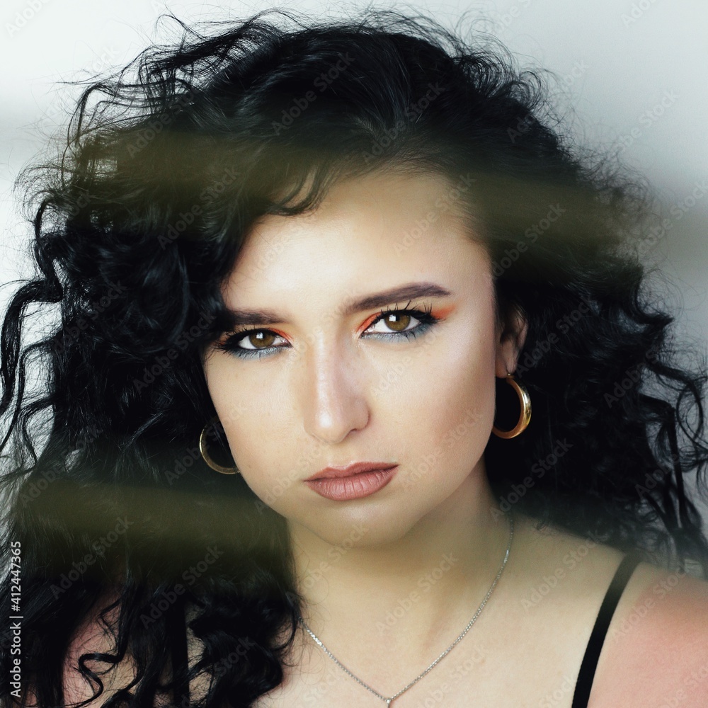 Beautiful young brunette model with bright make-up and curly hairstyle