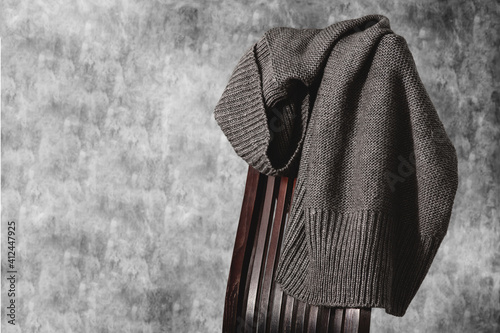Obraz na płótnie Knitted gray sweater on the back of wooden chair against gray concrete color wall. Minimal style. Copy space. w salonie