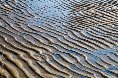 Wavy sand texture created by ocean waves. Beautiful patterns in the sand formed by wind on the beach sand texture