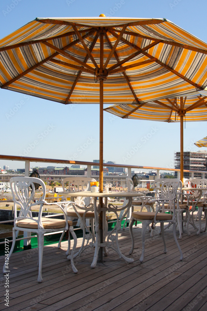 Elegant cast iron deck chairs and tables with sun umbrellas on outdoor