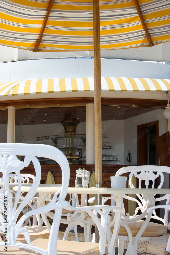 Elegant cast iron deck chairs and tables with sun umbrellas on outdoor