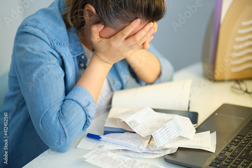 sad woman holding the bills to calculate in living room at home. Expenses, account, taxes, home budget concept.