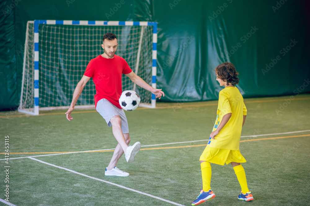 Fototapeta premium Boy in yellow uniform playing soccer with his coach