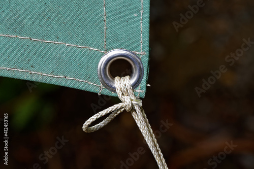A metal eyelet in a tarpaulin keeps it securely fastened