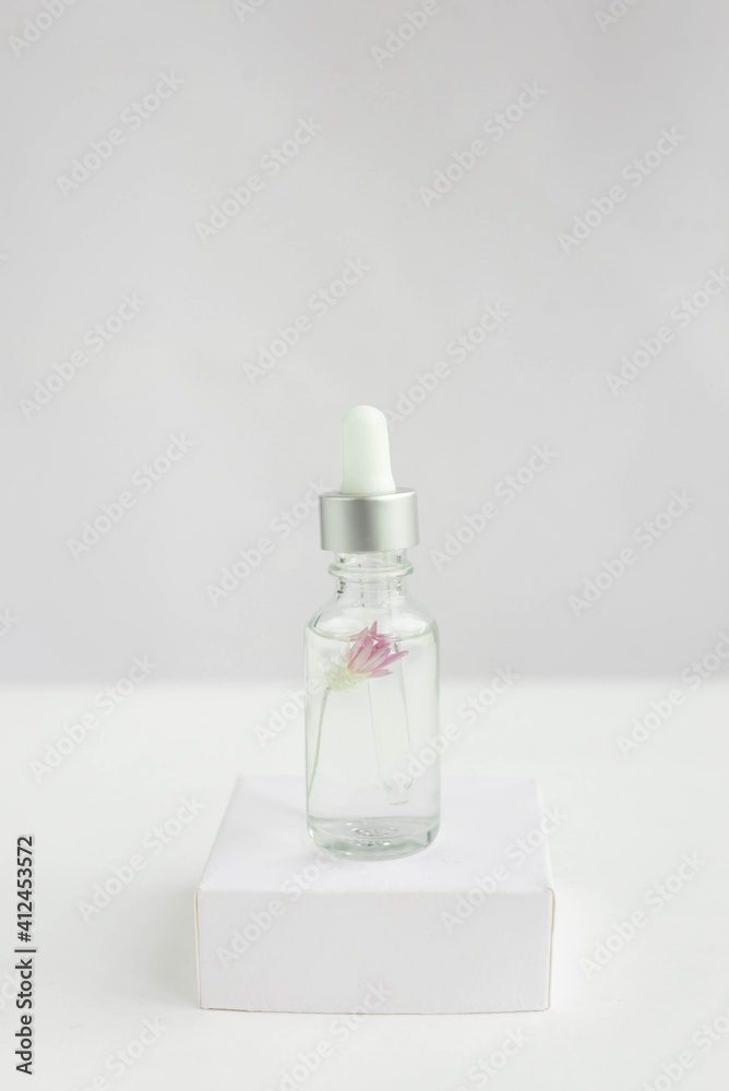 Glass jar for natural cosmetics on a white background on a white podium with a flower inside. Trendy minimalistic abstract collection. The beauty of a woman. Natural background. Glass jar for natural cosmetics on a white background on a white podium with a flower inside. Trendy minimalistic abstract collection. The beauty of a woman. Natural background.