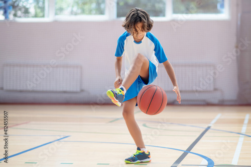 Schoolboy in sportswear training his basketball skills in a gym © zinkevych