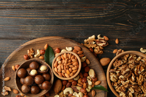 Tray with bowls with different nuts on wooden background