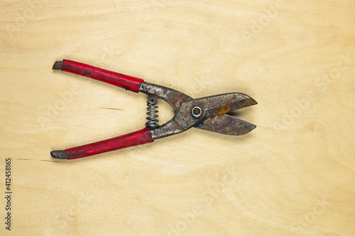 Rusty metal sheet cutter scissors on a wooden background
