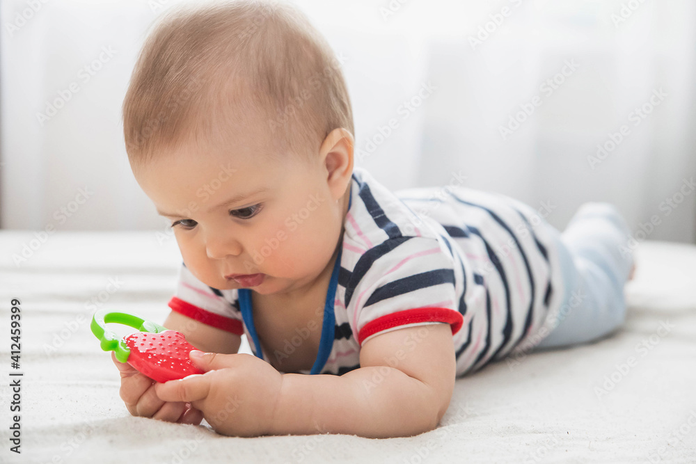 baby is nibble a rubber toy because the child’s teeth are being cut baby is nibble a rubber toy because the child’s teeth are being cut