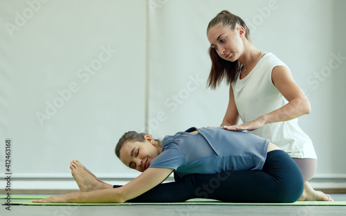 Good shape female Yoga master helps the new goga primary student to practice basic gesture and correct to body pose. Concept for learning new skill in class for health and mind