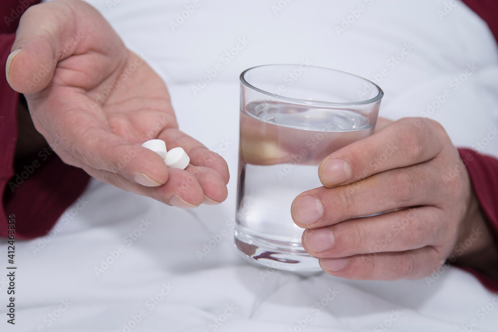 man in bed with glass of water and pills man in bed with glass of water and pills