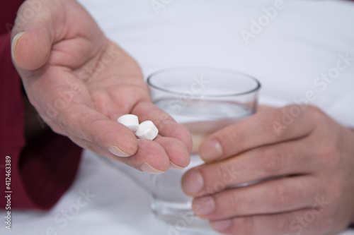 man in bed with glass of water and pills