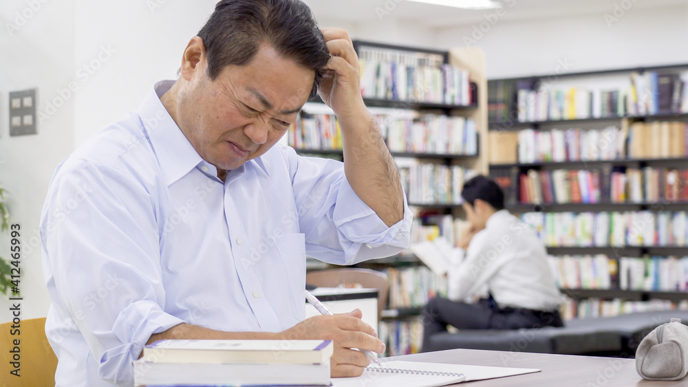 図書館で勉強する中高年男性 図書館で勉強する中高年男性
