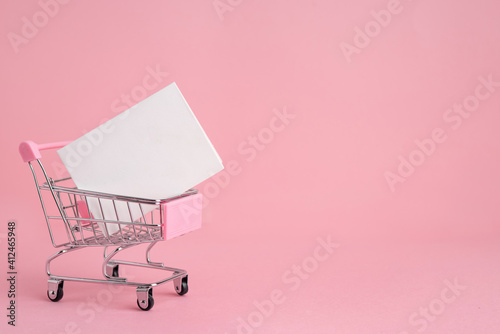Shopping cart with white postcard on pink for web design, banner. Valentine's Day, Wedding, Birthday, International Women's Day. Copy space.