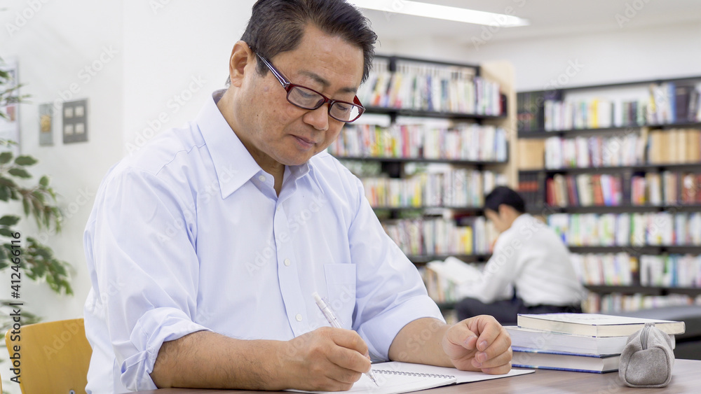 図書館で勉強する中高年男性 図書館で勉強する中高年男性