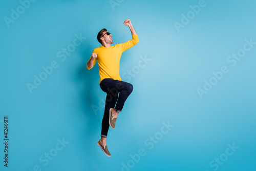 Fototapeta Naklejka Na Ścianę i Meble -  Full length profile portrait of delighted guy jump fists up open mouth shout yes isolated on blue color background