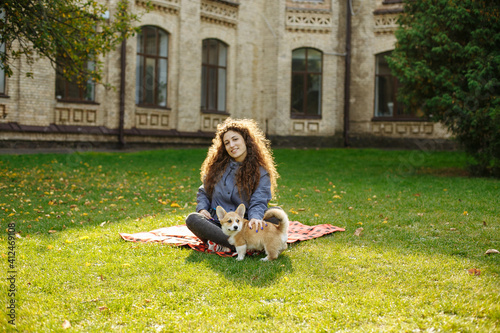 girl on a red plaid playing with a puppy
