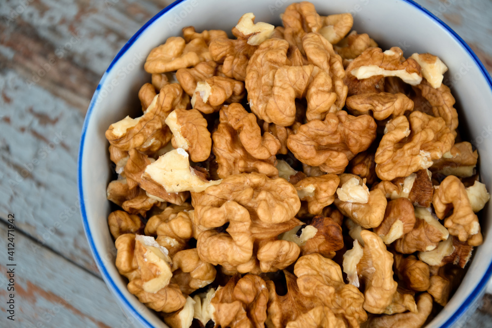 Walnuts. Walnut kernels. Clean organic walnuts. Nuts in the cup on vintage blue wooden background. Walnut tree fresh fall harvest. Walnuts. Walnut kernels. Clean organic walnuts. Nuts in the cup on vintage blue wooden background. Walnut tree fresh fall harvest.