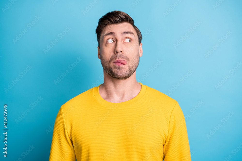 Portrait of attractive cheerful funny crazy guy grimacing looking aside isolated over bright blue color background Portrait of attractive cheerful funny crazy guy grimacing looking aside isolated over bright blue color background