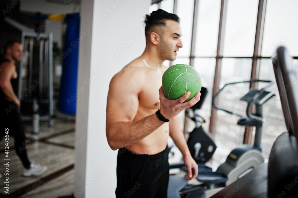 Muscular arab man training in modern gym. Fitness arabian men with naked torso doing exercises with ball. Muscular arab man training in modern gym. Fitness arabian men with naked torso doing exercises with ball.