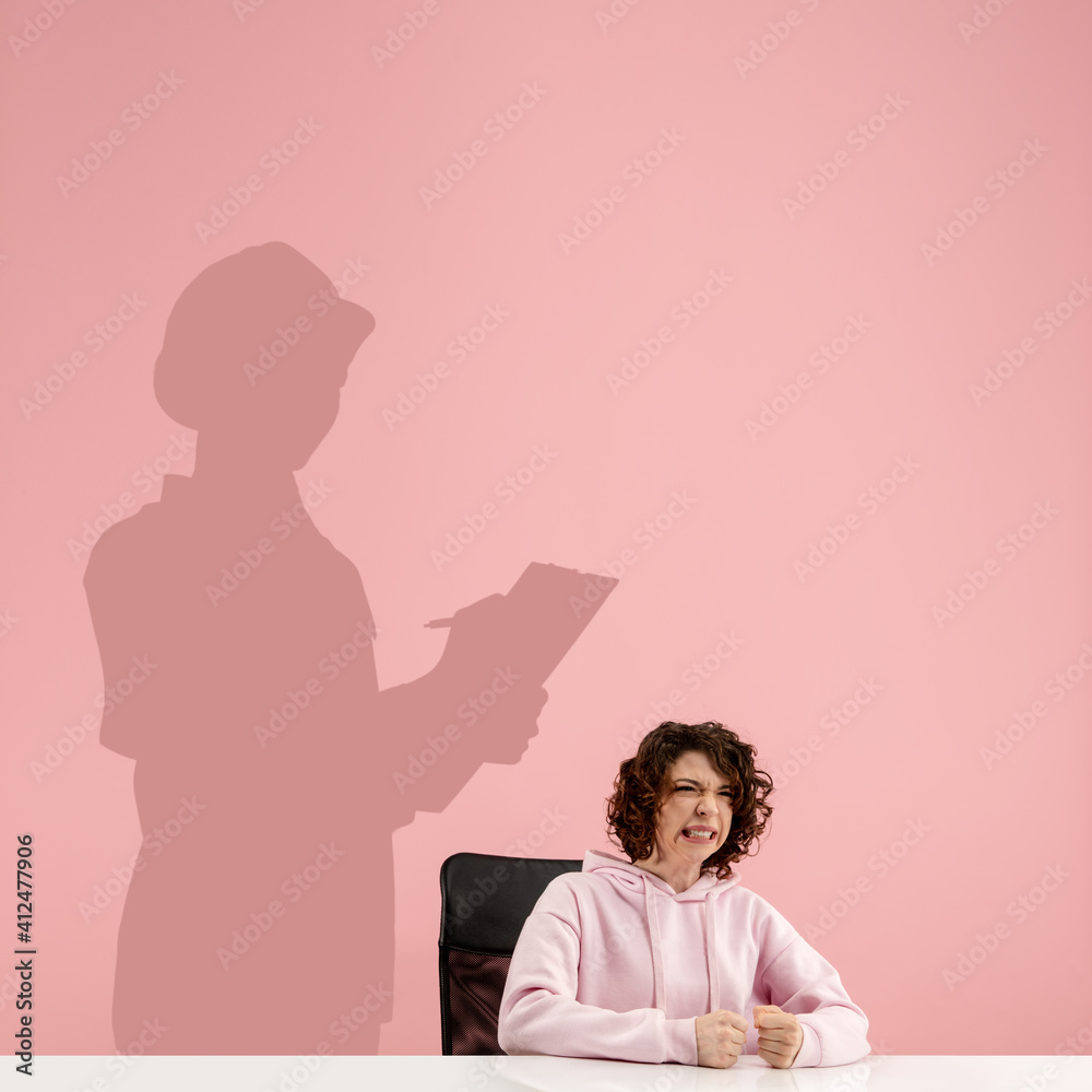 Young caucasian woman dreaming about future in big science during her work in office. Shadow, silhouette of female builder, ingeneer on the wall. Becoming a legend. Inspiration, aspiration. Copyspace. Young caucasian woman dreaming about future in big science during her work in office. Shadow, silhouette of female builder, ingeneer on the wall. Becoming a legend. Inspiration, aspiration. Copyspace.