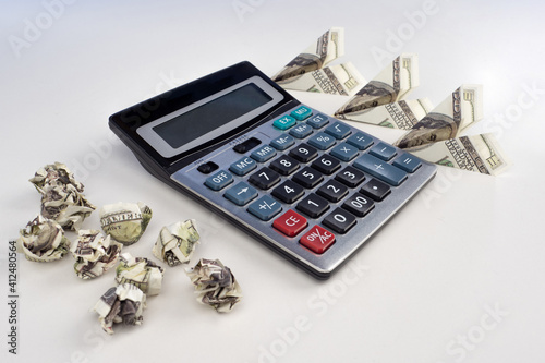 Money next to the calculator. Crumpled bills as a symbol - losses. Airplanes made of dollars as a symbol - profit. Analysis of chords and expenses. Investment Efficiency Analysis. Passives and assets photo