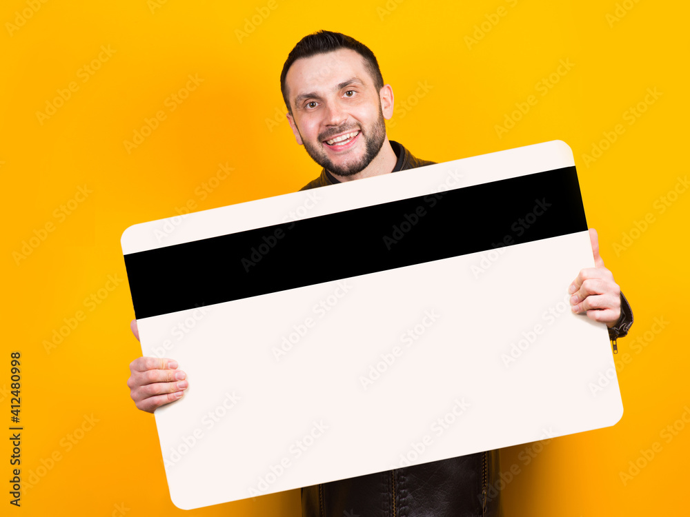 Cheerful man holding a huge bank card in his hands Cheerful man holding a huge bank card in his hands