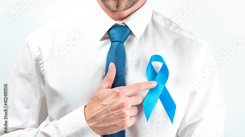 November. Hipster men in bright shirt, cyan tie with blue ribbon in hands on white background. Awareness prostate cancer of men health. Supporting people living and illness.