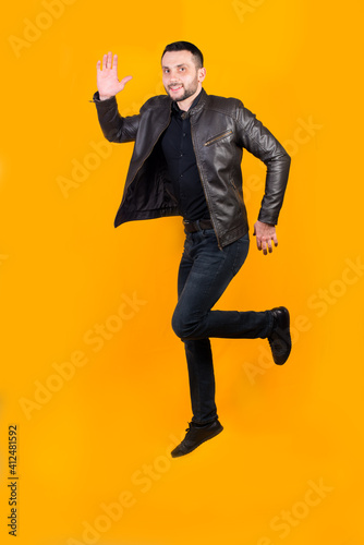 Cheerful positive man jumped on orange background