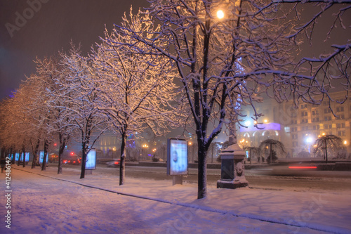 Snowy trees and cars on a night street