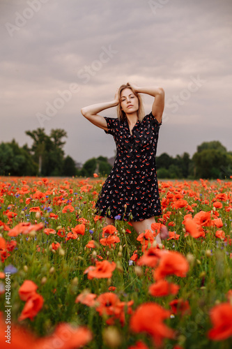 girl in a black dress in a field of poppies