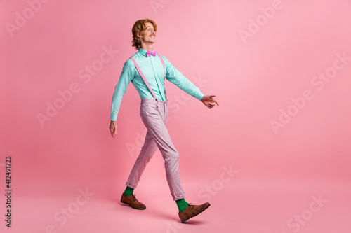 Full size profile photo of satisfied young man walking look empty space isolated on pink color background