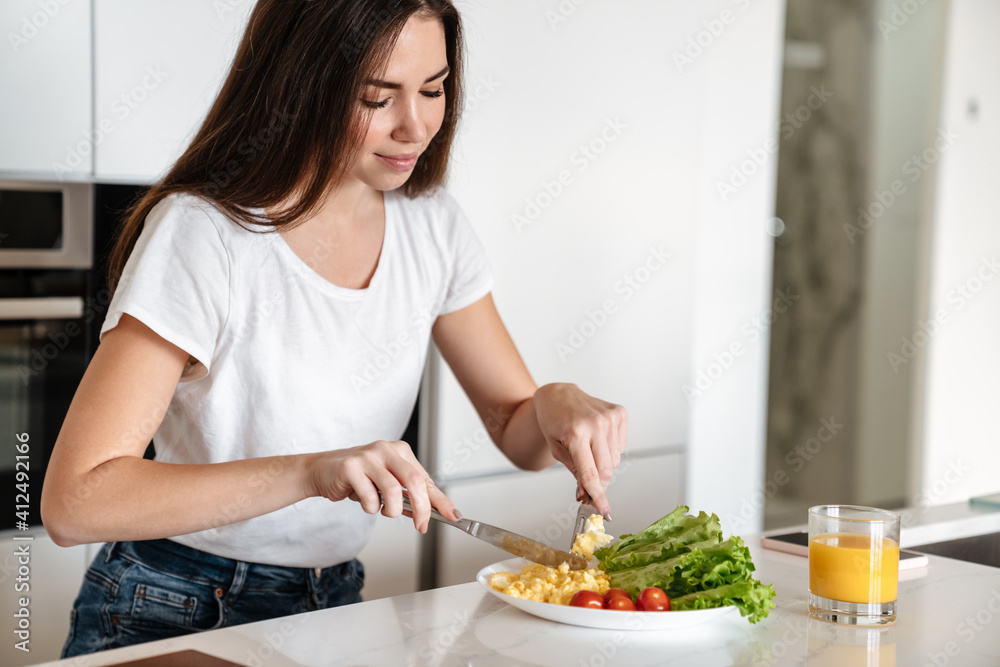 Joyful caucasian woman smiling while having lunch at home kitchen Joyful caucasian woman smiling while having lunch at home kitchen