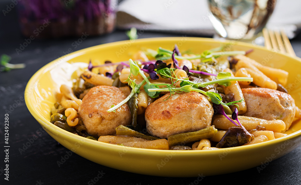 Caserecce pasta with meatballs in  sweet and sour sauce and vegetables in bowl.