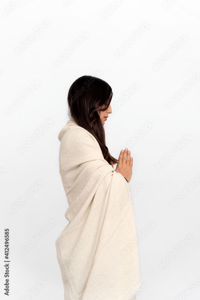 Woman in activewear and shawl meditating with namaste hands in white background during yoga session Woman in activewear and shawl meditating with namaste hands in white background during yoga session