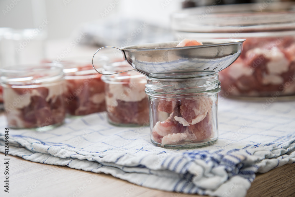 Schulter Fleisch roh in Schraubglas und Trichter zum selbstgemacht Einkochen Einwecken für Russisch Tuschonka Schweinefleisch im eigenen Saft in Küche