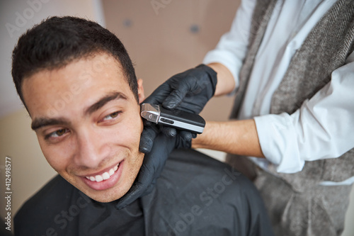 Barber holding electrical machine and making styling of hair and beard