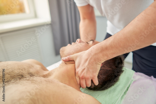 A professional massage therapist in a medical center does neck-collar zone massage on a patient.