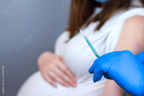 Fotografie Doctor giving COVID -19 coronavirus vaccine injection to pregnant woman