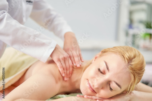 Women's hands of a specialist massage the woman's back. Therapeutic massage for spinal scoliosis.