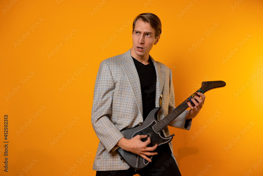 stylish and cool guy in a suit and with a game guitar on a yellow background, have fun and have a good time stylish and cool guy in a suit and with a game guitar on a yellow background, have fun and have a good time