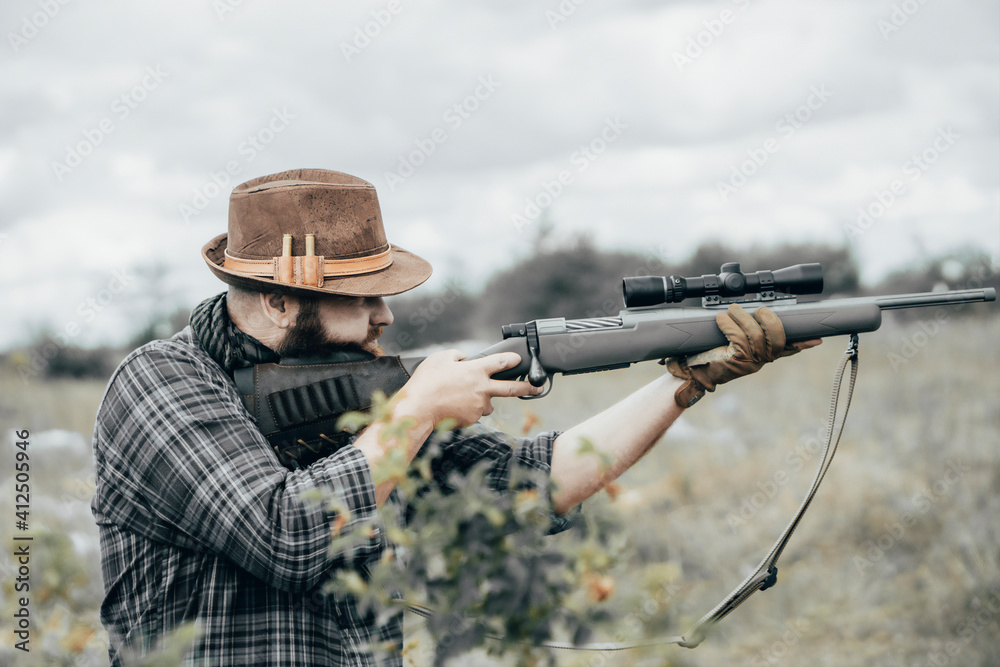 Fototapeta premium Man shoots a rifle. Bearded man with scout rifle