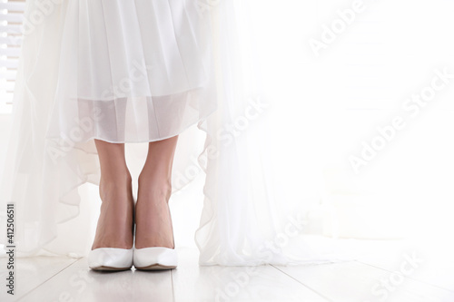 Young bride wearing beautiful wedding shoes indoors, closeup. Space for text