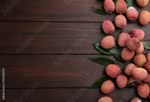 Fresh ripe lychee fruits on wooden table, flat lay. Space for text