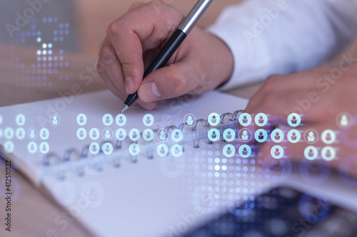HR specialist is taking notes concerning new candidates to create international network in recruitment process. Concept of success. Social media hologram icons. Formal suit