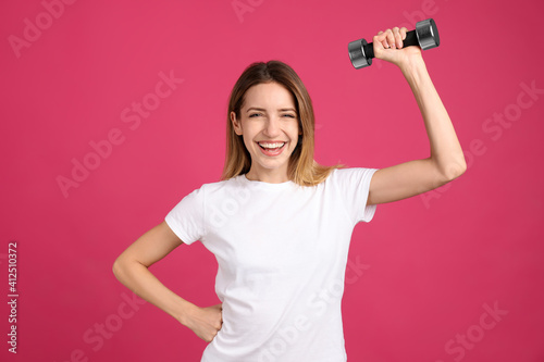 Woman with dumbbell as symbol of girl power on pink background. 8 March concept © New Africa